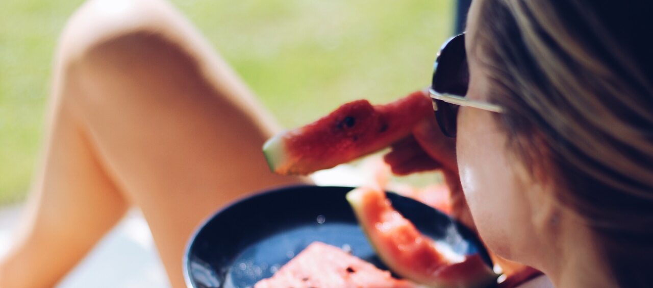 mulher comendo fatias de melancia de biquini