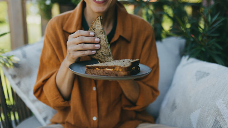 mulher segurando um sanduíche sentada ao ar livre