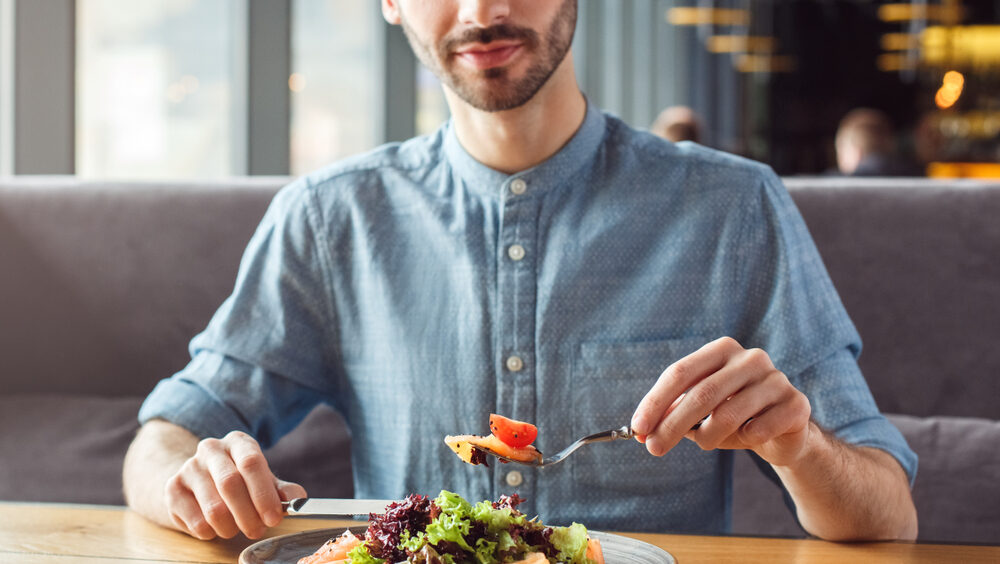 homem de camisa azul comendo refeição saudável