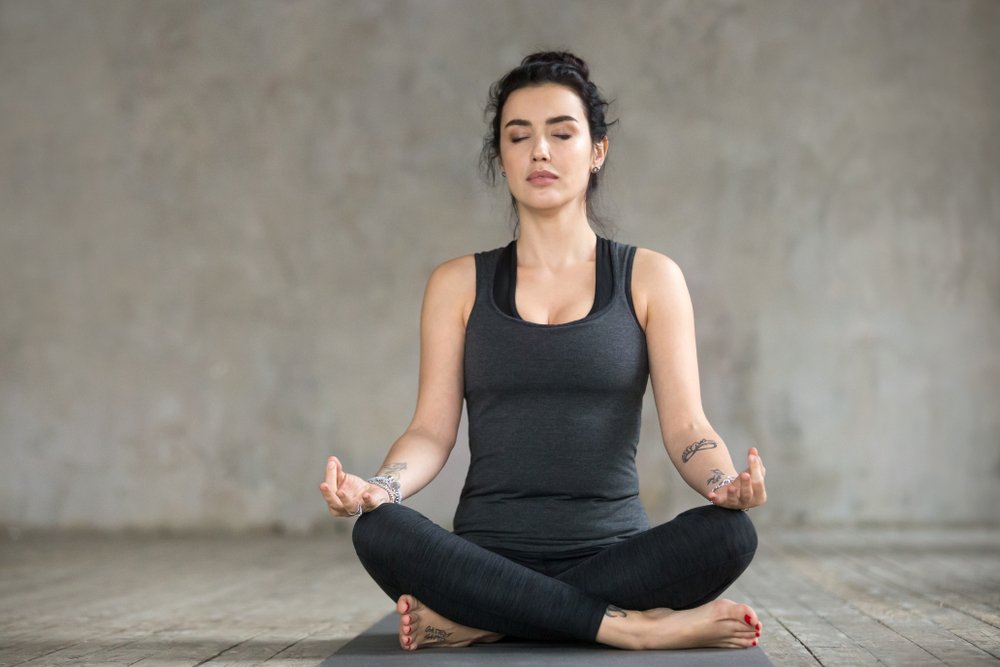 mulher vestindo roupas de treino sentada e meditando