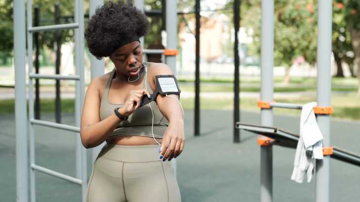 mulher em um parque arrumando a braçadeira de colocar celular e fazer exercícios físicos