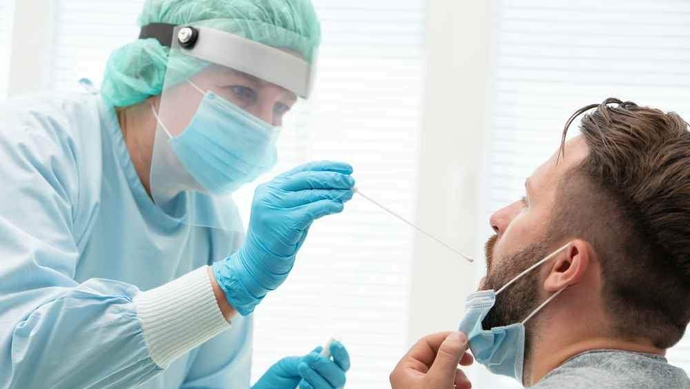 ômicron enfermeira faz teste de covid-19 em homem