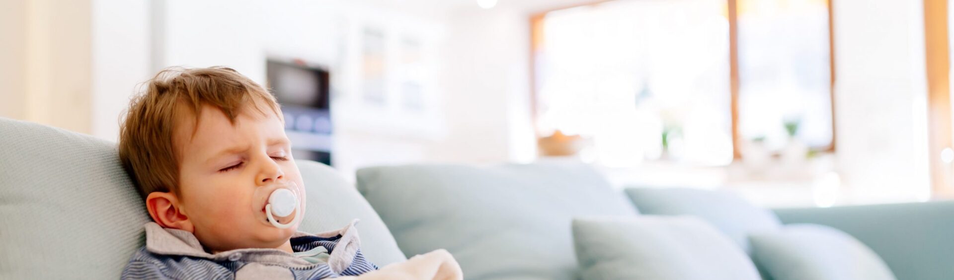 criança pequena deitada em um sofá azul