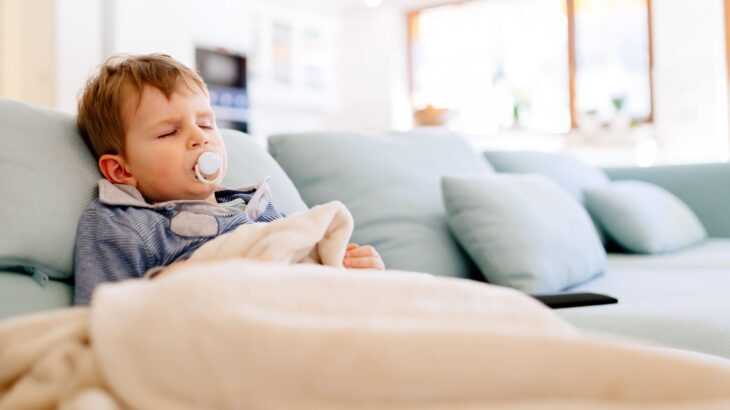 criança pequena deitada em um sofá azul