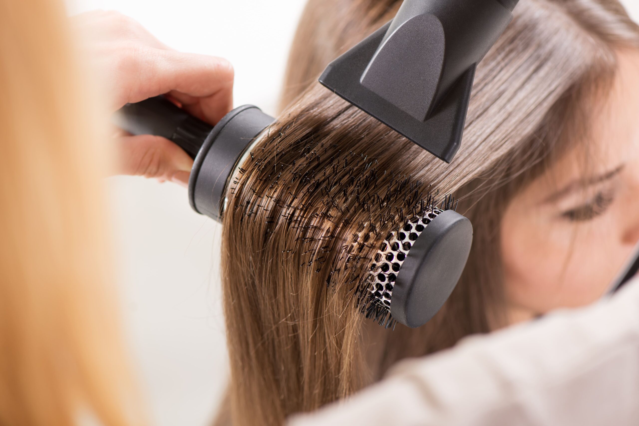 O cabeleireiro usa um secador de cabelo e modela o cabelo de uma