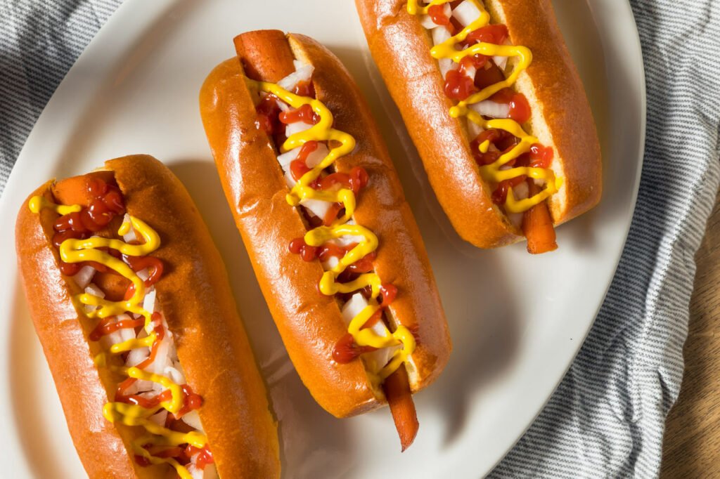 foto de um cachorro-quente com cenouras dentro do pão no lugar da salsicha, além de ketchup e mostarda