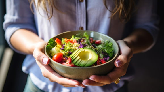 mulher segurando um pote com hortaliças e frutas, que fazem parte da dieta plant-based