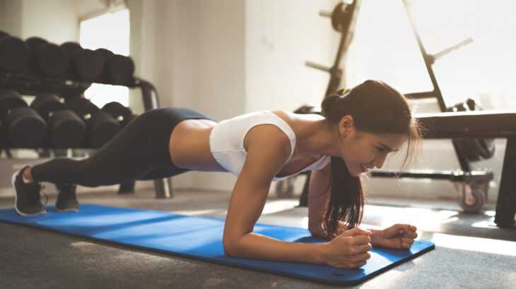mulher fazendo o exercício prancha abdominal na academia