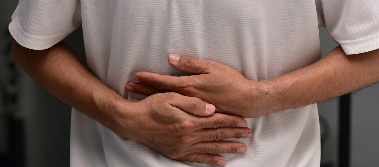 imagem mostra apenas o tronco de um homem com as mãos na barriga, como se estivesse sofrendo com uma crise de gastrite