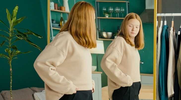 Menina de cabelos vermelhos se olhando no espelho