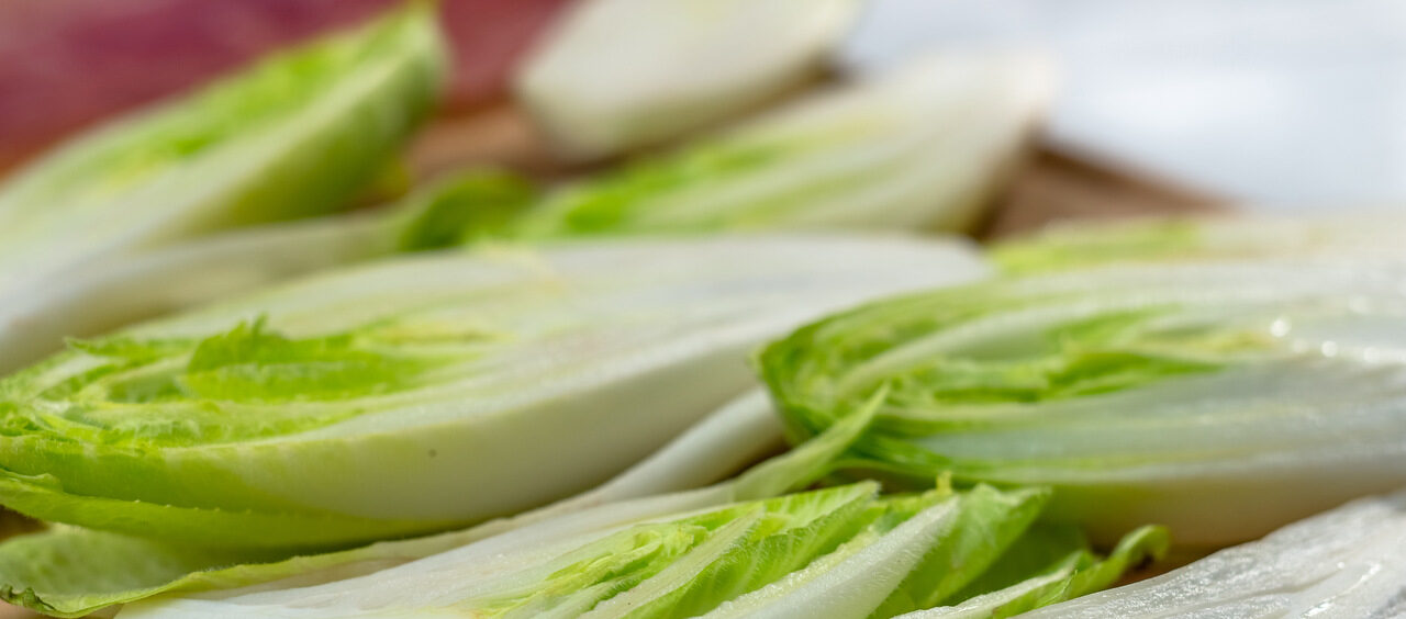 chicórias cortadas ao meio em cima de uma tábua de madeira