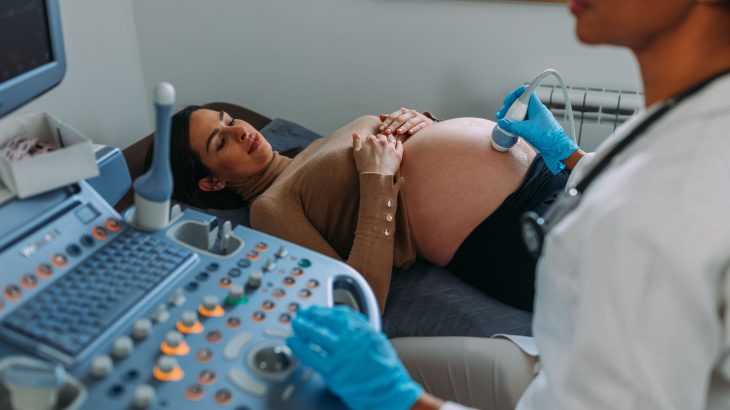 médica realizando o ultrassom em uma grávida na clínica