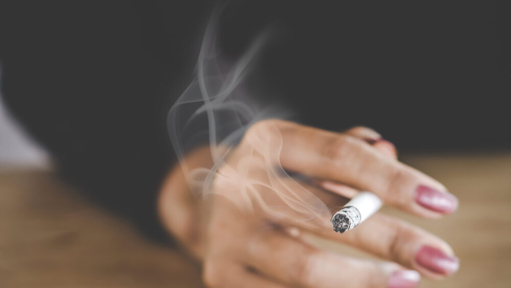 mão feminina segurando um cigarro aceso