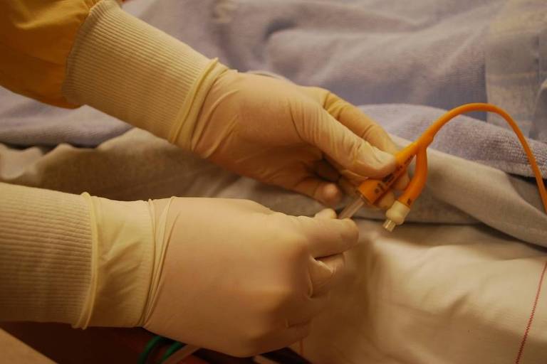 mãos de um médico ou enfermeiro mexendo no cateter de um paciente