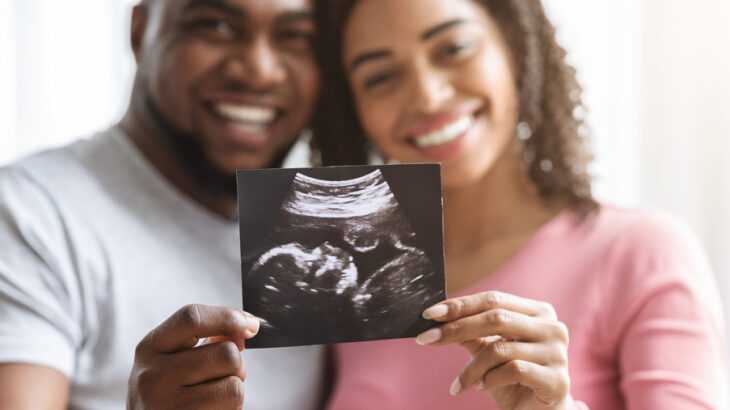 casal heterossexual segurando a imagem de um ultrassom fetal