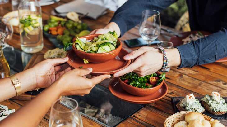 mesa farta de alimentos veganos com pessoas se servindo