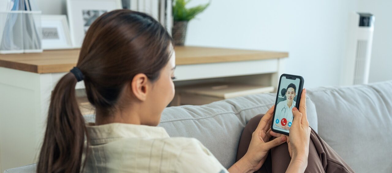 mulher no sofá de casa fazendo uma consulta virtual com um médico