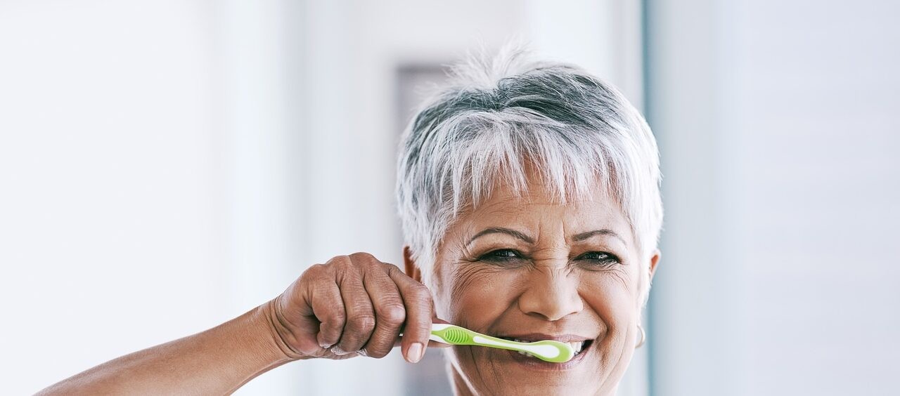 mulher mais velha escovando os dentes