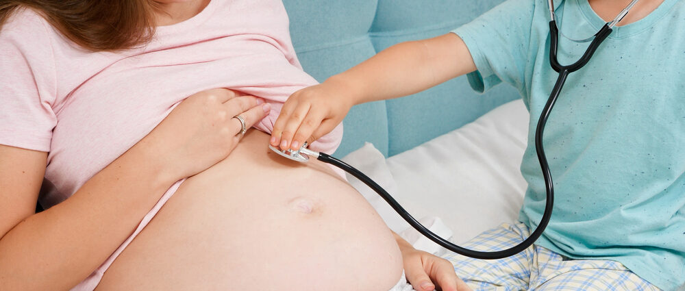 médica auscultando barriga de gestante