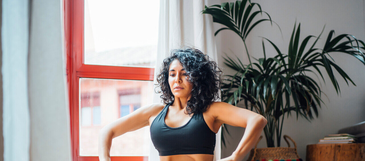 mulher praticando um exercício de abdominal hipopressivo em casa