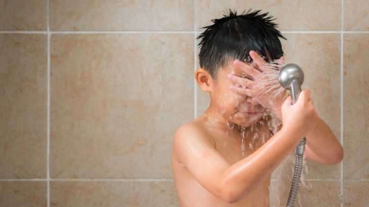criança tomando banho com um chuveirinho