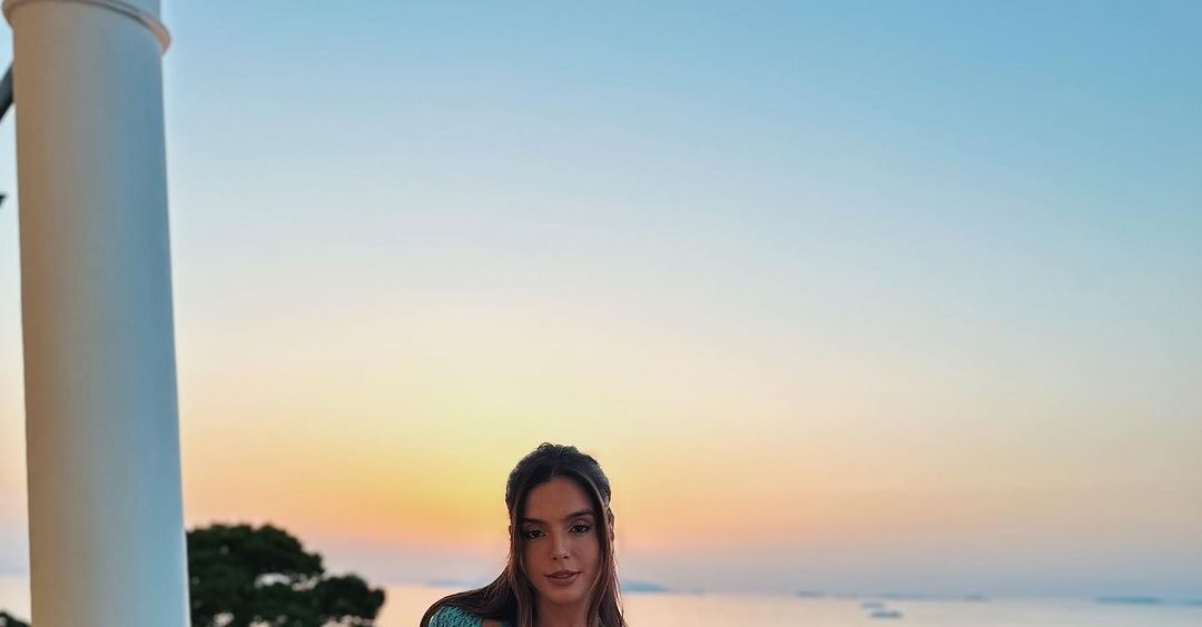 atriz Giovanna Lancellotti posando para a foto. Atrás, uma paisagem praiana