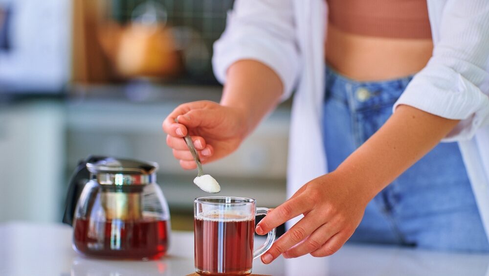 mãos femininas adoçando um café