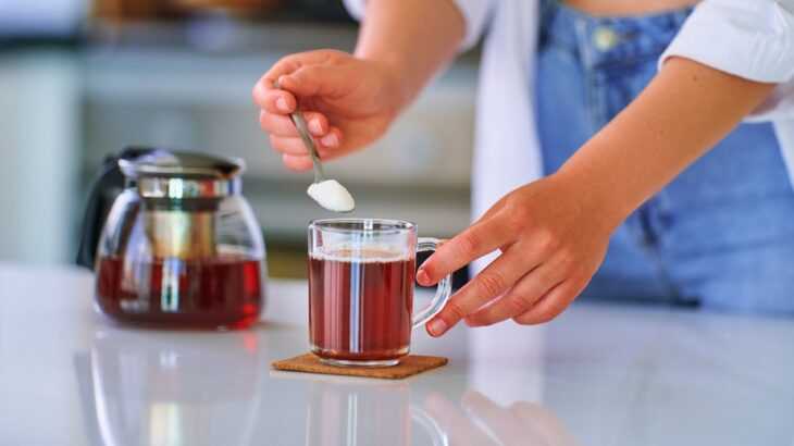 mãos femininas adoçando um café