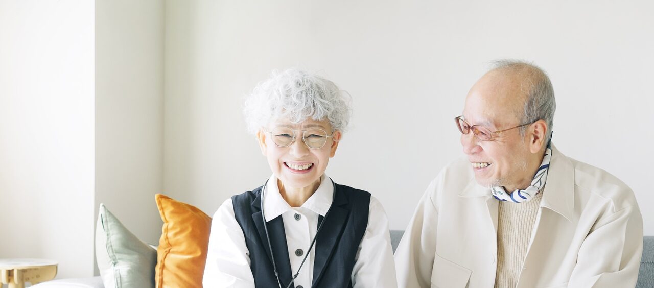 casal de idosos orientais sentados no sofá e sorrindo