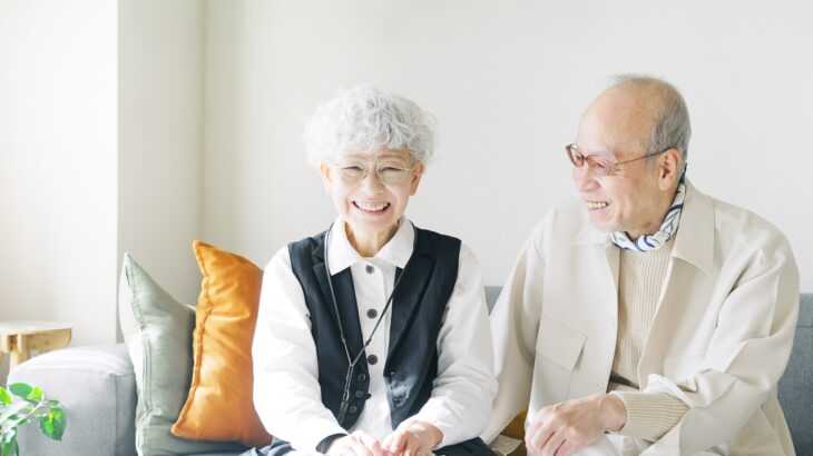 casal de idosos orientais sentados no sofá e sorrindo