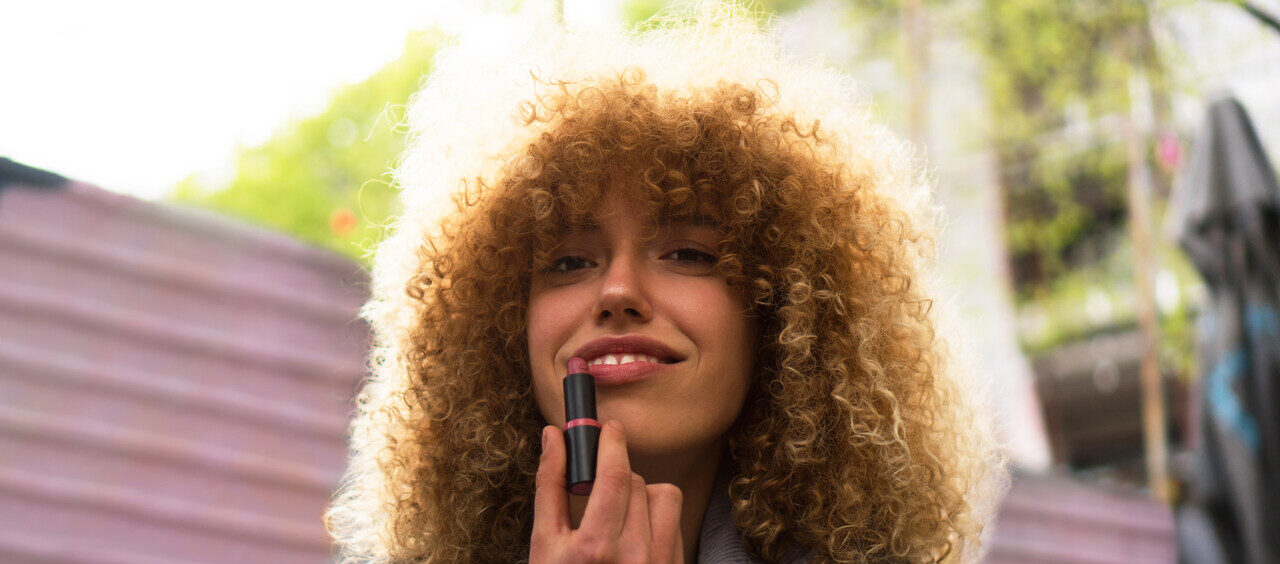 mulher passando batom nos lábios em um dia ensolarado