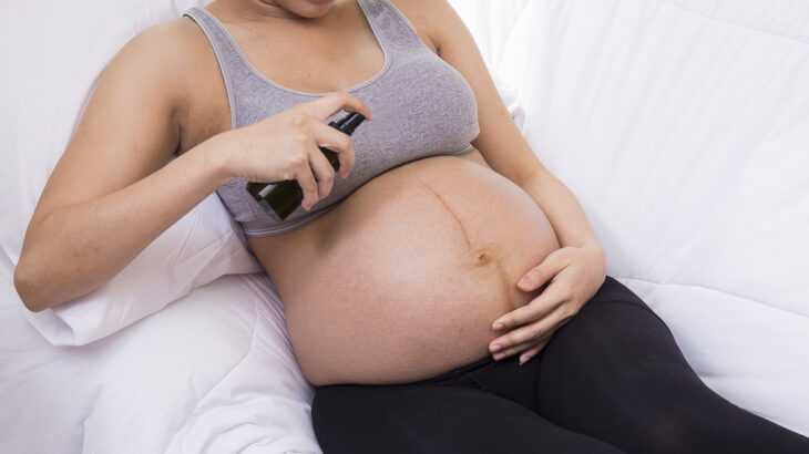 mulher grávida passando repelente na barriga