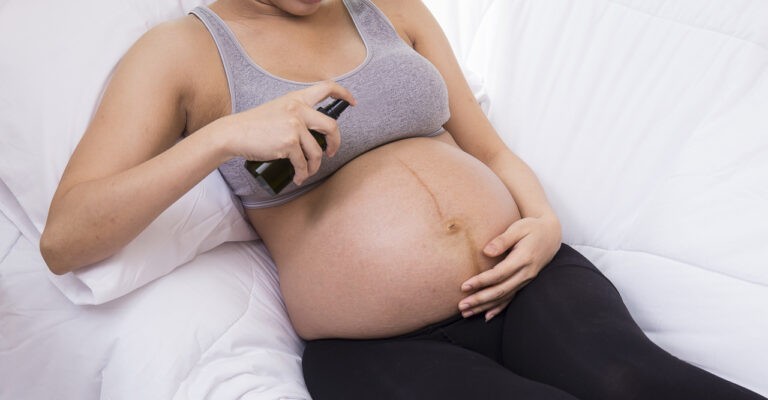 mulher grávida passando repelente na barriga