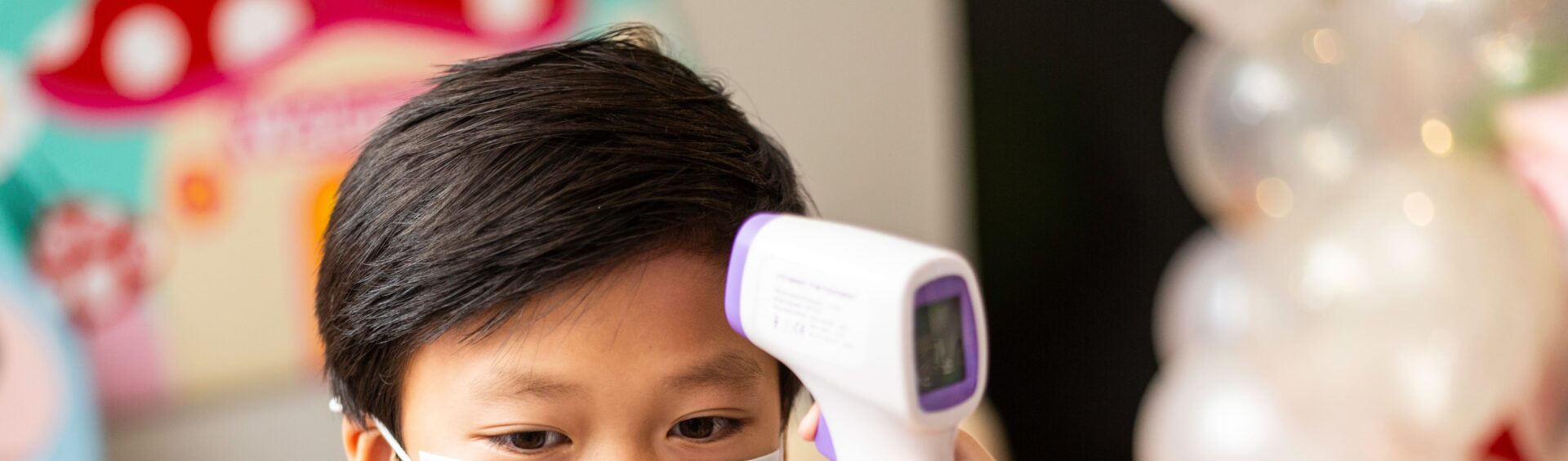 criança chinesa tendo sua temperatura medida