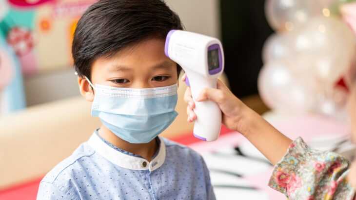 criança chinesa tendo sua temperatura medida