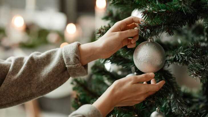 mãos de mulher arrumando a decoração de Natal na árvore