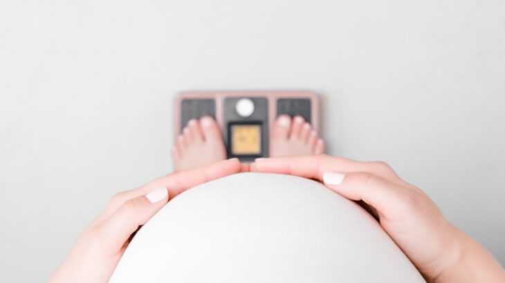 barriga de grávida vista de cima pesando em uma balança