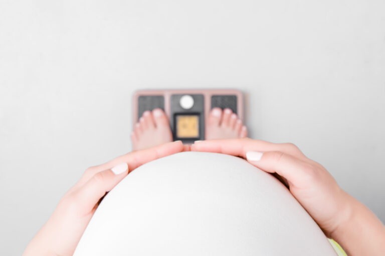 barriga de grávida vista de cima pesando em uma balança