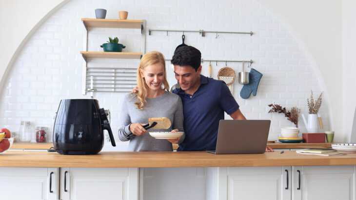 casal preparando comida na cozinha ao lado da air fryer