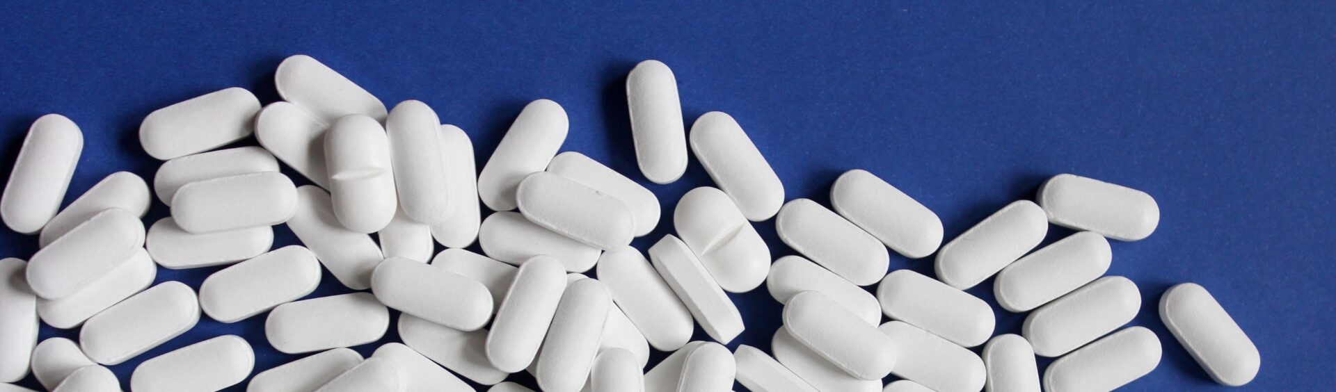 várias pílulas brancas em cima de um plano azul