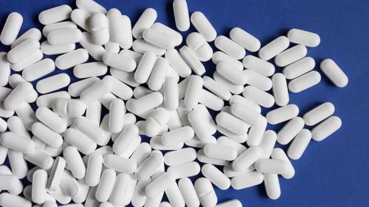 várias pílulas brancas em cima de um plano azul