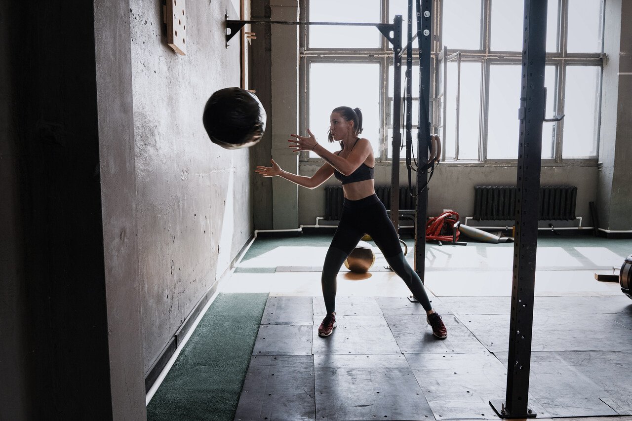 mulher fazendo um exercício com a medicine ball da parede do box de crossfit