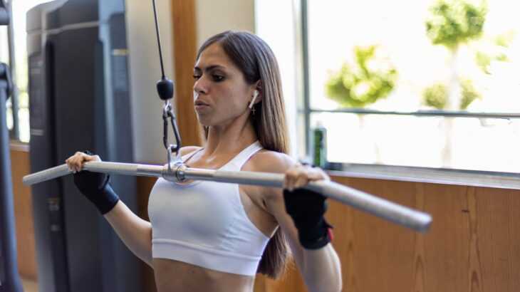 mulher na academia fazendo um exercício para costas em um aparelho