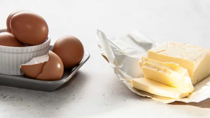 foto mostra ovos crus ao lado de um tablete de manteiga