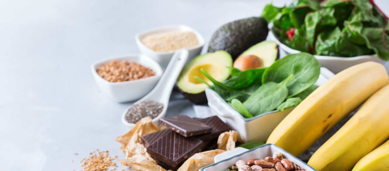 foto mostra diferentes alimentos fontes de magnésio, como banana, amêndoas, chocolate amargo, abacate, espinafre