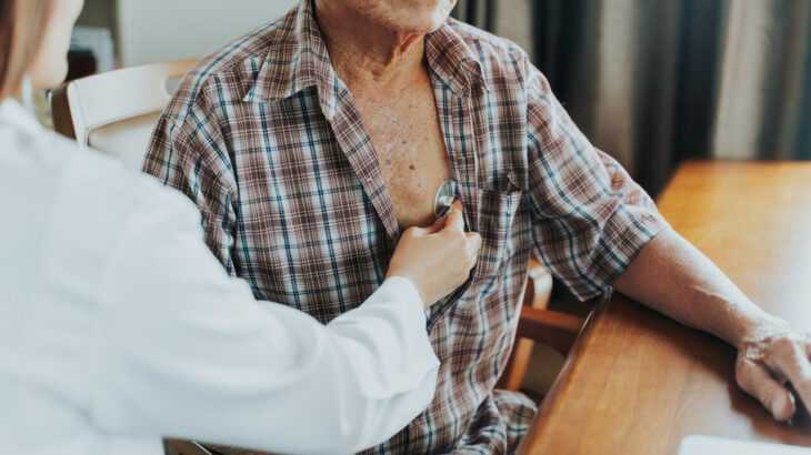 a foto mostra um médico examinando o coração de um paciente idoso