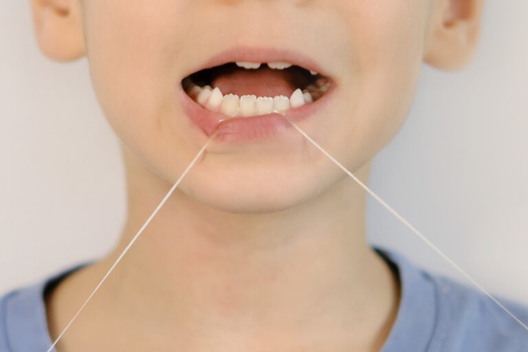 criança passando fio dental nos dentes