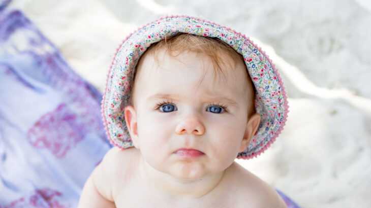 foto de um bebê com um chapéu na praia em um dia de calor