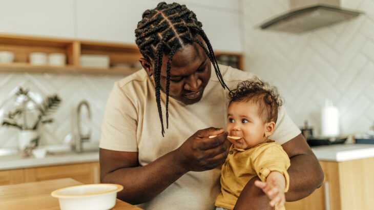 pai alimentando o seu filho no colo na cozinha