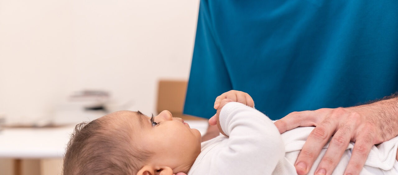 mãos de médico examinando um bebê na maca